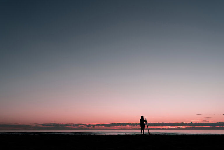 Portrait von Surferin zum Sonnenuntergang in Silhouette