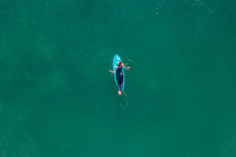 Surferin paddelt ins Line Up