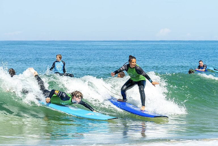 Surfschüler surfen eine Welle