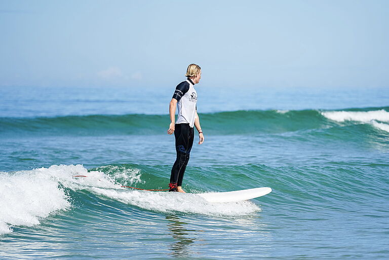 Surflehrer surft eine grüne Welle