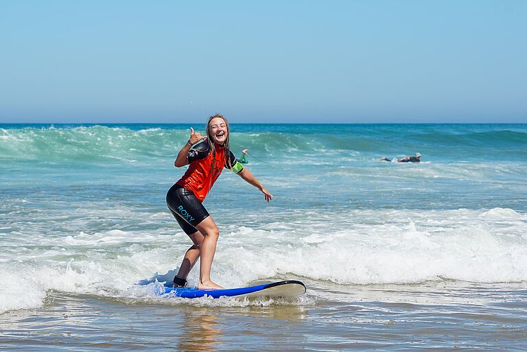 Surfschülerin steht eine Welle