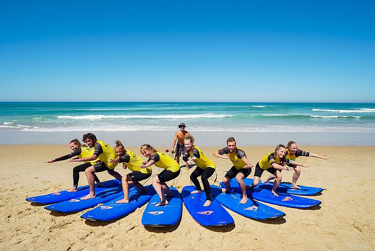 Gruppenfoto eines Surfkurses mit Surflehrer