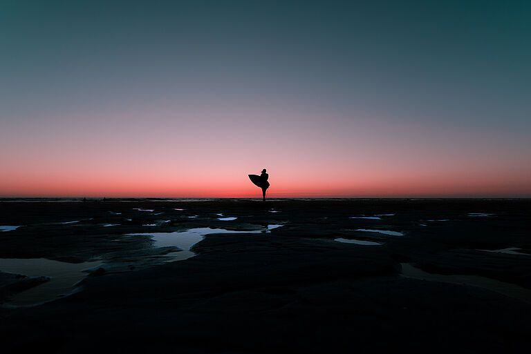 Silhouetten-Foto von Surferin zum Sonnenuntergang
